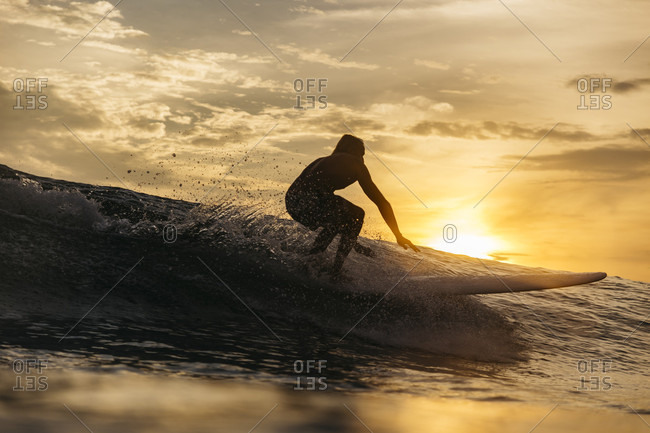 Silhouette of male surfer riding wave in sea at sunset,ÔøΩÔøΩÔøΩChanggu, Bali, Indonesia