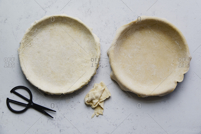 Raw uncooked pie crust in baking pan for two pies on concrete background