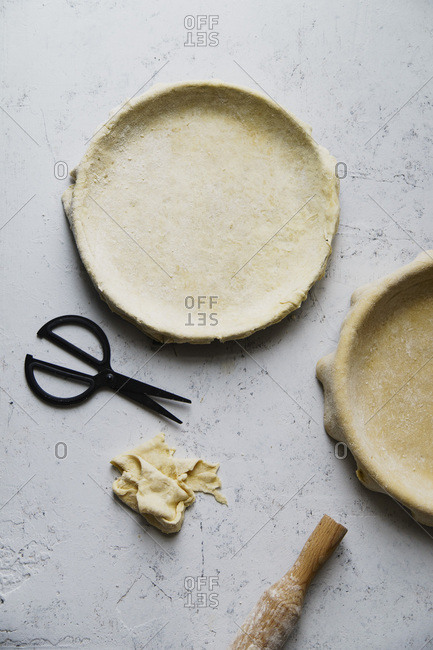 Raw uncooked pie crust in baking pan for two pies on concrete background