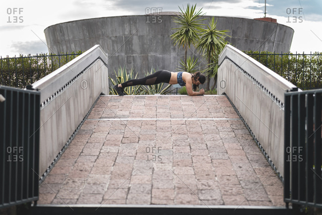 Side view of Latino woman doing plank on footbridge in Mexico city