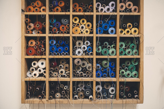 Colorful thread spools in rack at upholstery workshop
