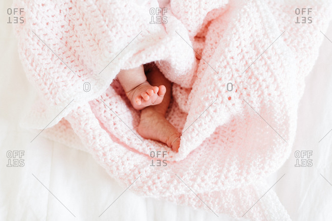 Baby's little bare feet wrapped in pink crocheted blanket