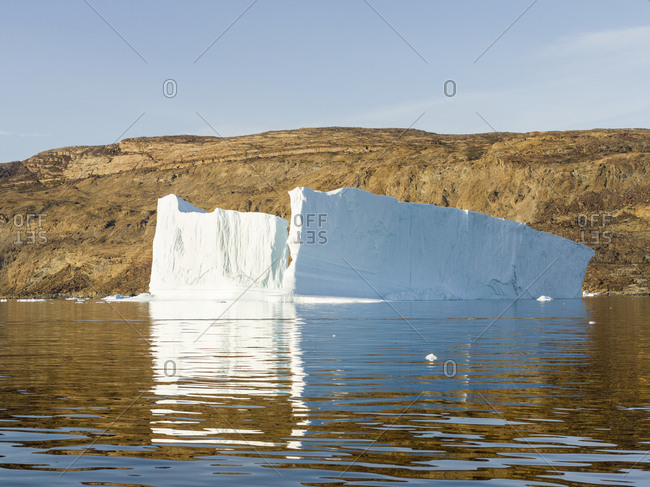 Landscape with steep yellow cliffs and icebergs in the Uummannaq fjord system, northwest Greenland.