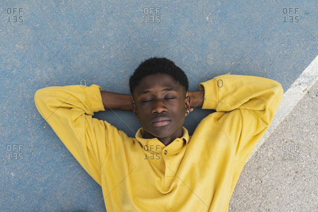 Young black man sleeping on floor- with hands behind head