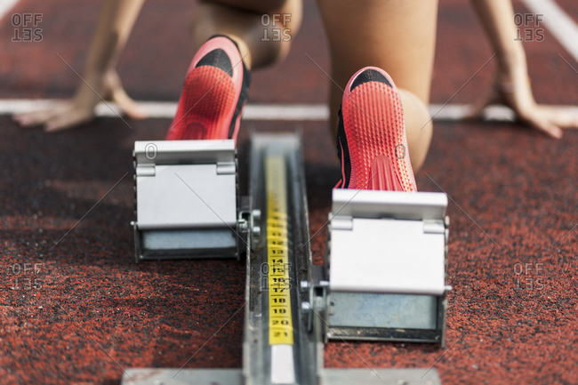 Teenage runner kneeling on starting block- close up