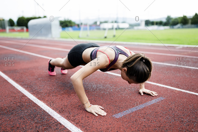 Teenage runner doing push ups on race track