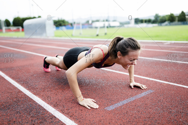 Teenage runner doing push ups on race track