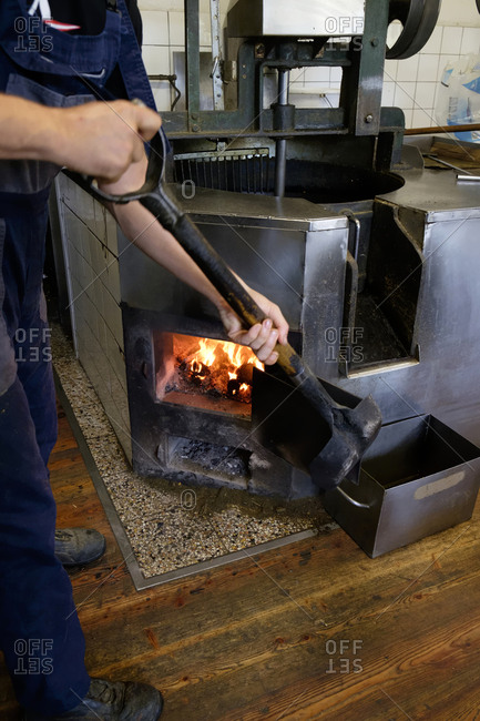 Man heating stirrer vessel with coal at an oil mill