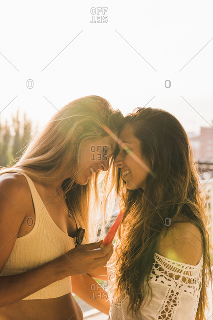 Happy lesbian couple with watermelon slice outdoors in sunlight