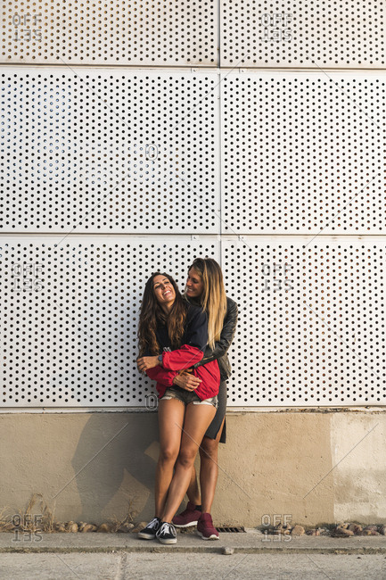 Happy lesbian couple hugging at a wall