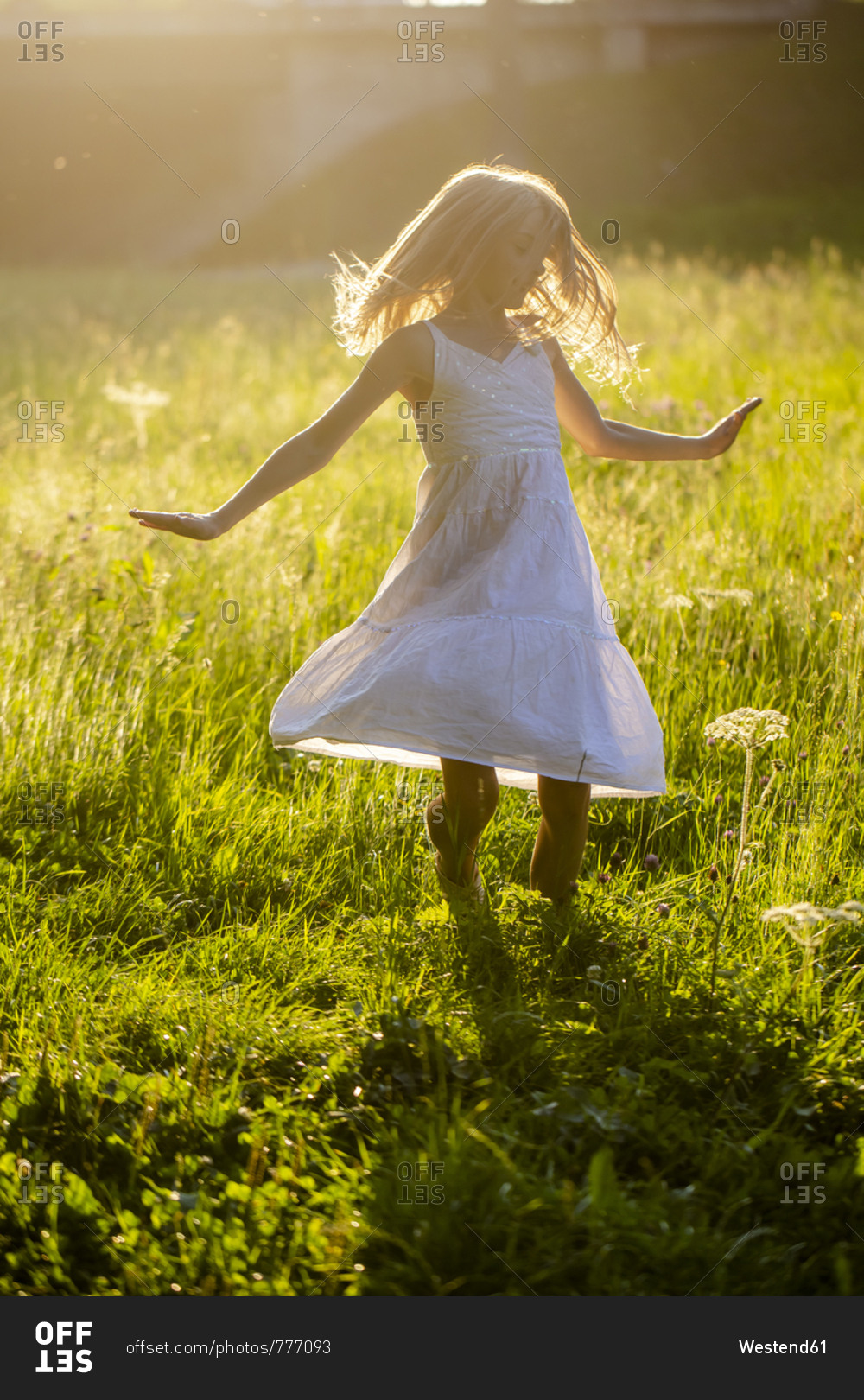 Happy girl dancing on summer meadow at backlight