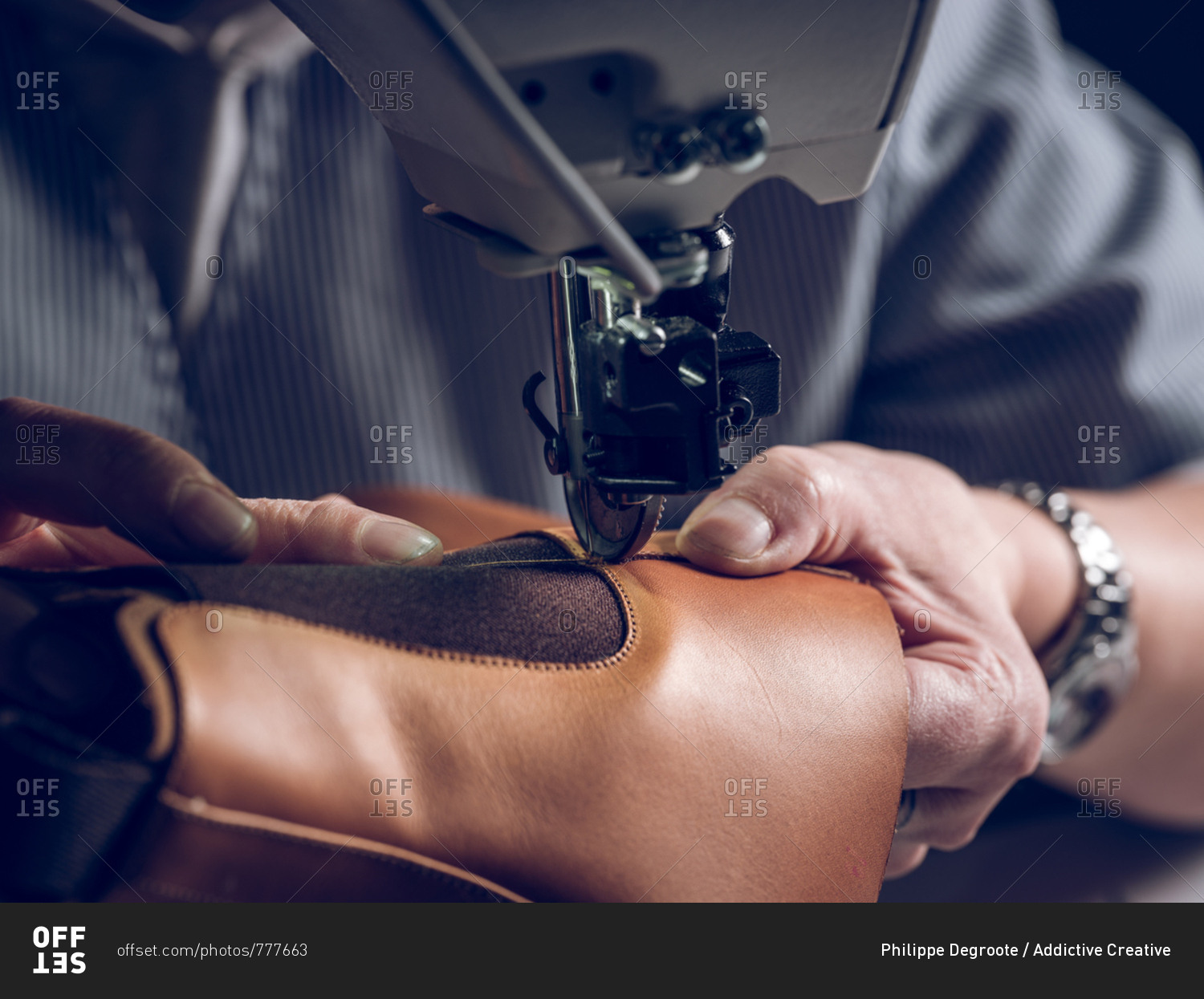 Unrecognizable man using professional machine to sew piece of brown leather for shoe