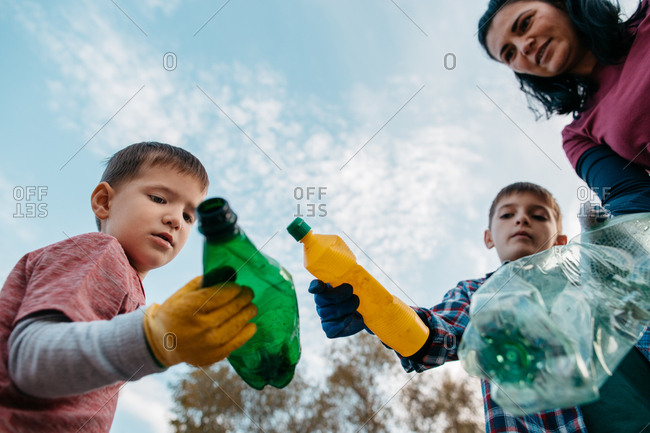 Low Angle Shot Of Woman And Her Sons Holding Plastic Bottles
