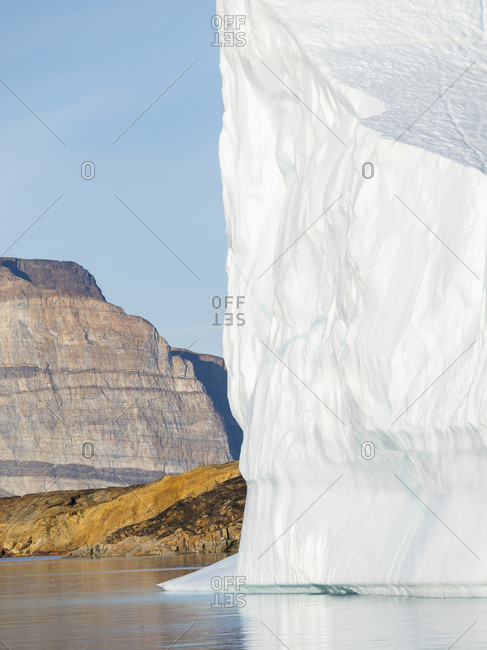 Landscape with steep yellow cliffs and icebergs in the Uummannaq fjord system, northwest Greenland.
