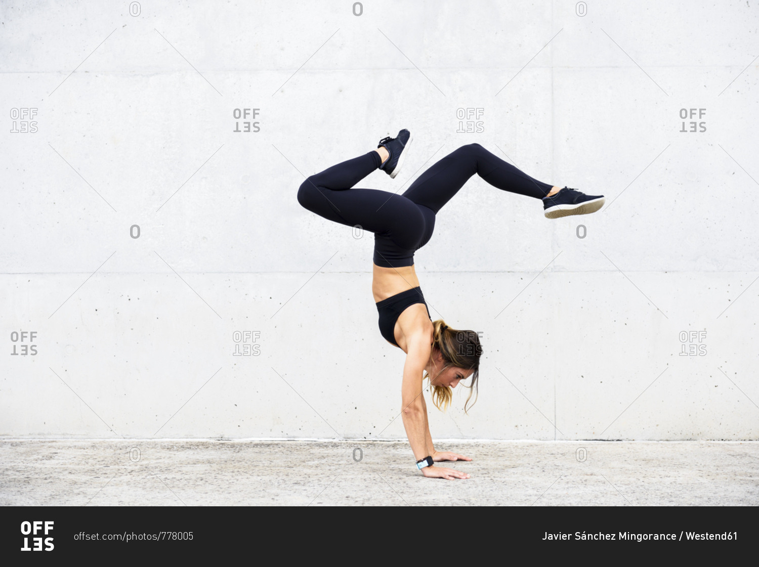 Athlete doing handstand in front of white wall
