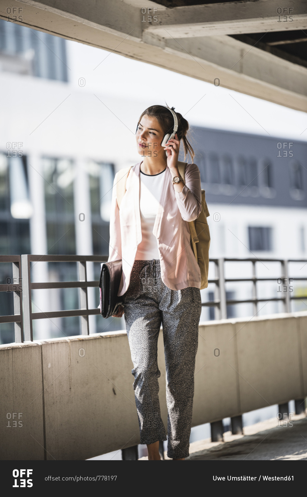 Young businesswoman walking in parking garage- listening music with her headphones
