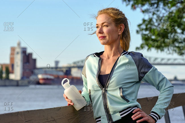 Female athlete having a water break watching sunset, Montreal, Quebec, Canada