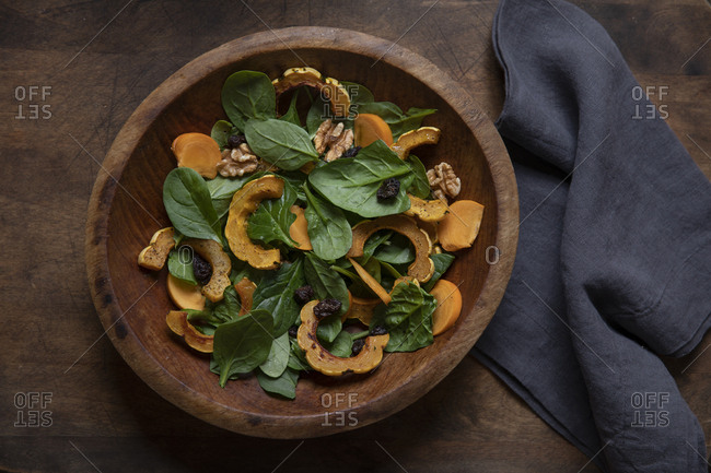 Delicata squash and spinach salad in wooden bowl