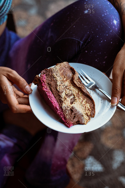 Person holding a plate with a slice of vegan chocolate cake