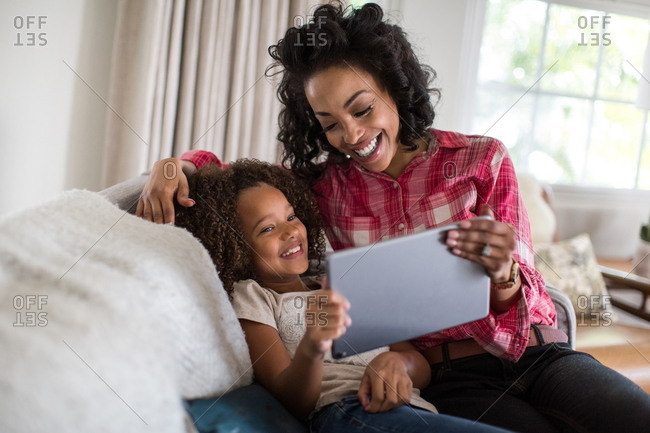 African American mother and daughter watching entertainment on digital tablet at home