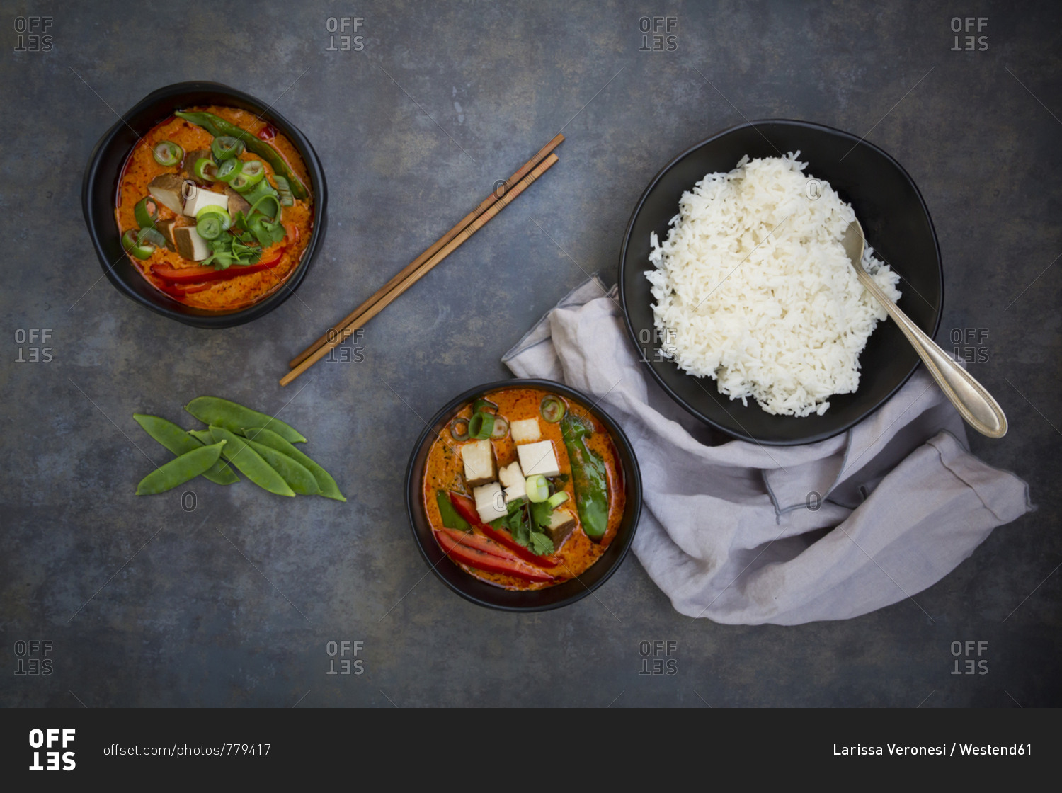 Two bowls of red Thai Curry with snow peas- carrots- bell pepper- spring onions and smoked tofu