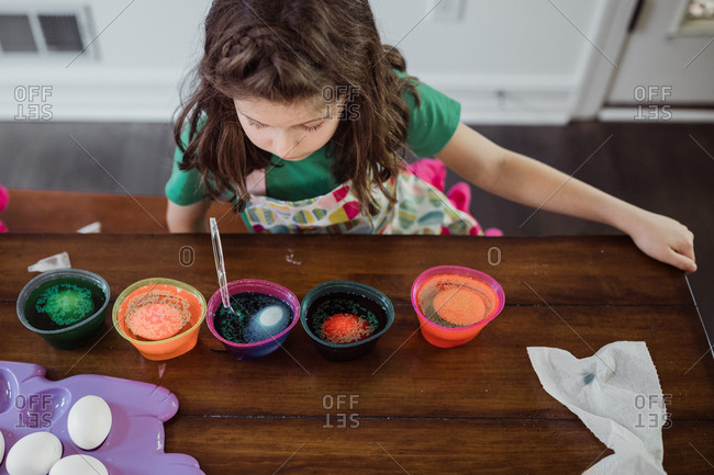 Girl watching her easter eggs changing color in dye