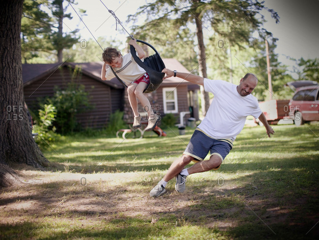 father pulls chld in tire swing