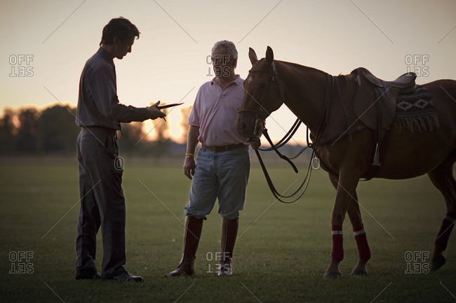 View of two men with a horse in the evening.