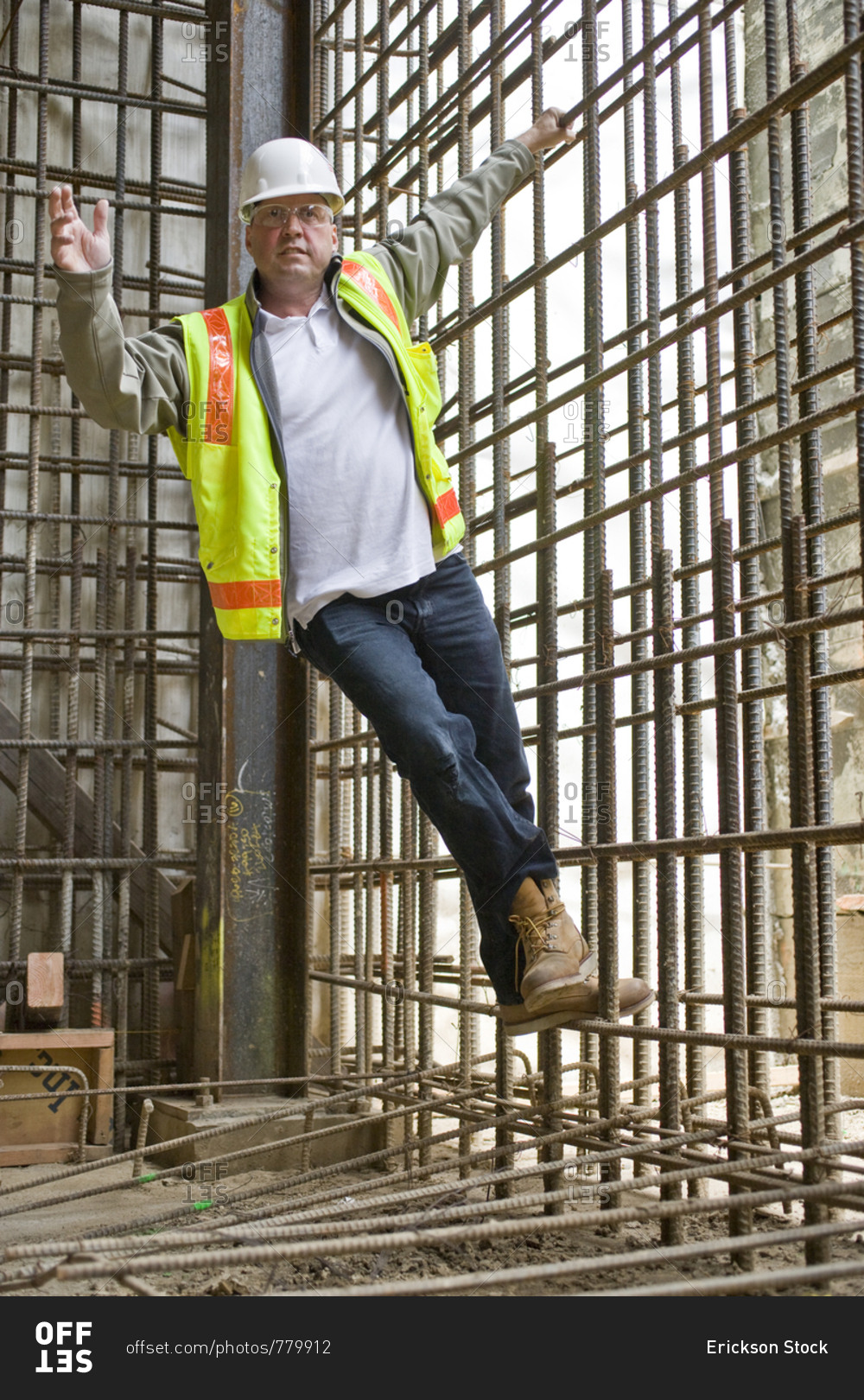 Portrait of a male construction worker hanging from a wire grid on a construction site.