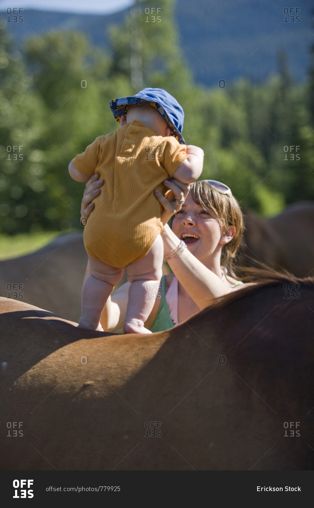 Mother standing baby up on the back of a horse