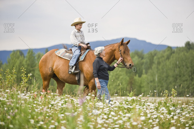 Grandmother leading horse ridden by grandson