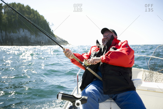 Mature adult man sitting on a boat fishing.