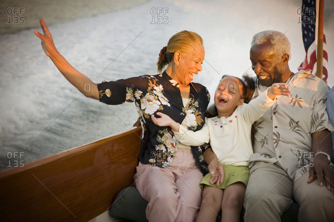 Mature adult couple sitting with their young granddaughter while on a boat.