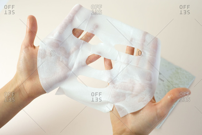 Hands holding a facial sheet mask