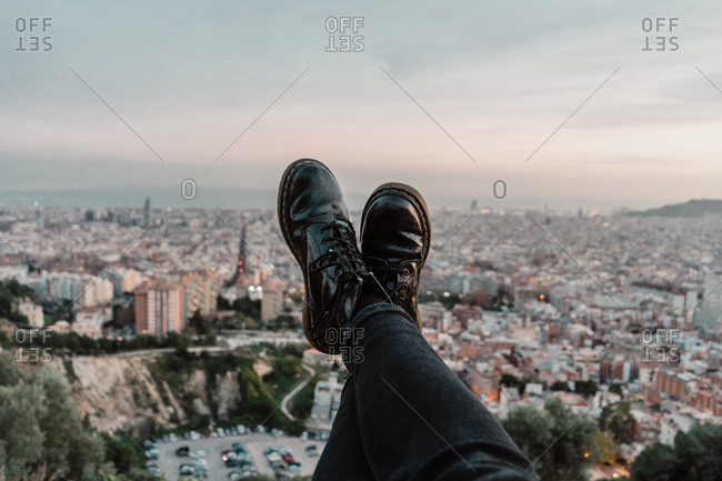 Feet of anonymous traveler against?beautiful metropolitan city and fantastic cloudy evening sky