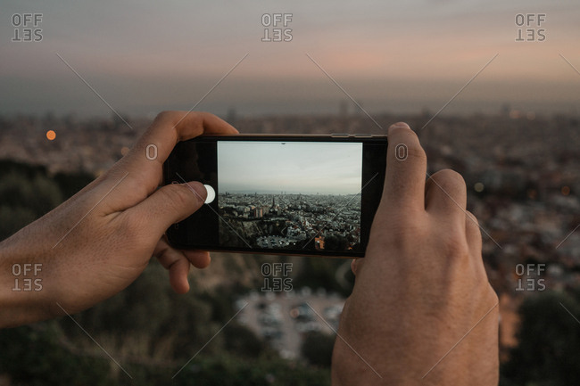 Man hands using modern smartphone to take pictures of amazing metropolitan city in wonderful cloudy evening