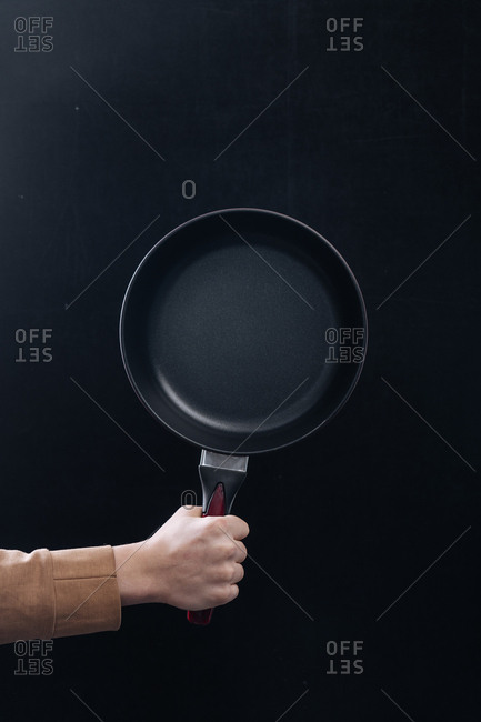 Chef holding a saute pan against a black background