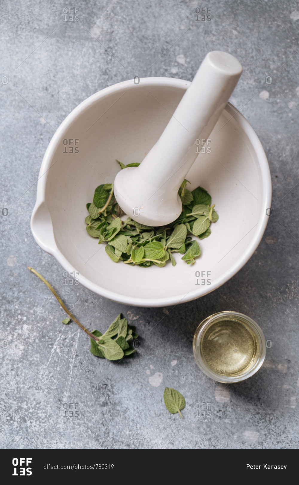 Herbs in a mortar with pestle and a small bowl of oil