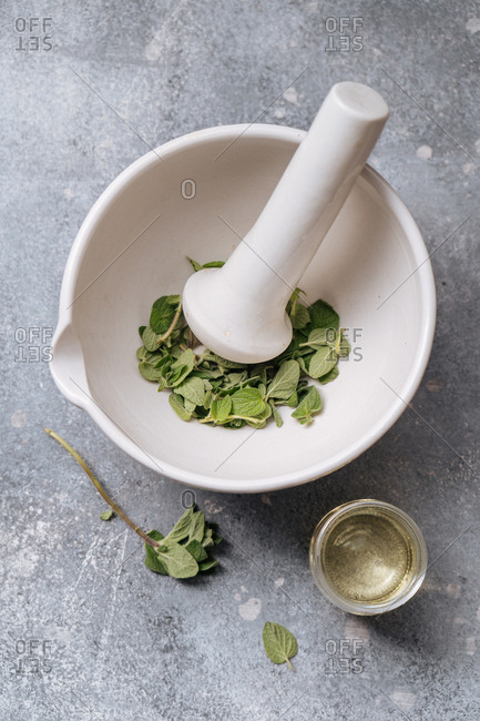 Herbs in a mortar with pestle and a small bowl of oil