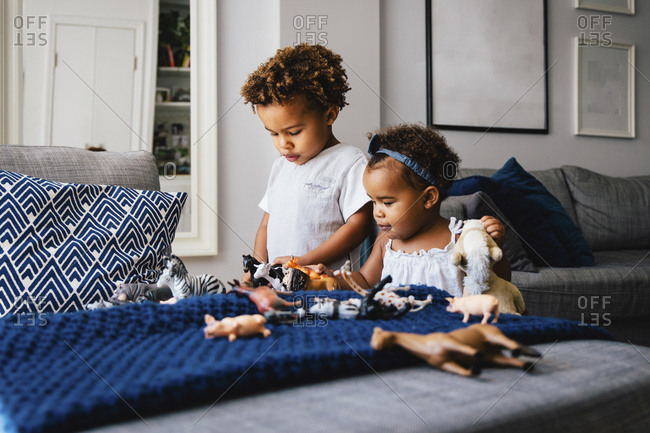 Cute siblings playing with toys on sofa at home