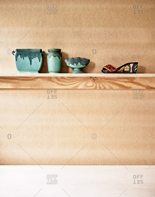 Wooden shelf with green pottery and a shoe