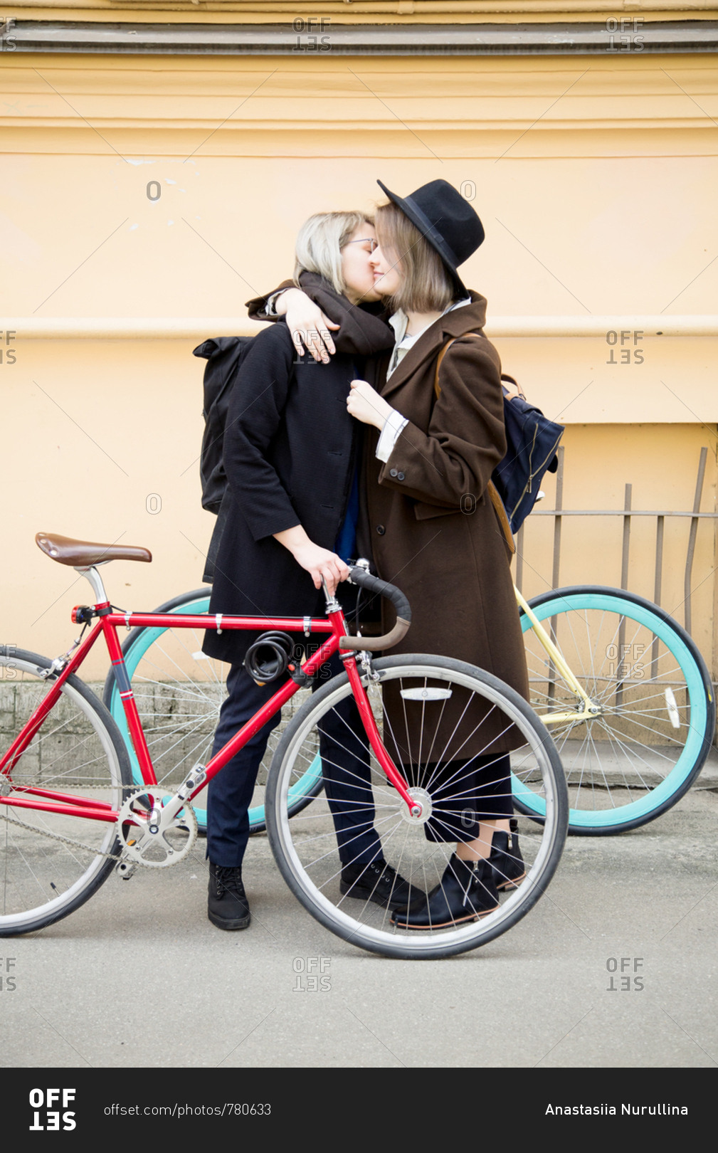 Lesbian Couple Kissing While Walking At The City Street With Bicycles