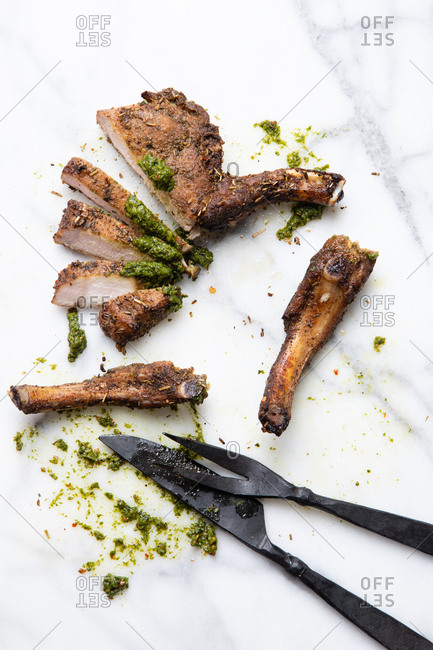 Pork chop and chimichurri sauce on a white marble surface