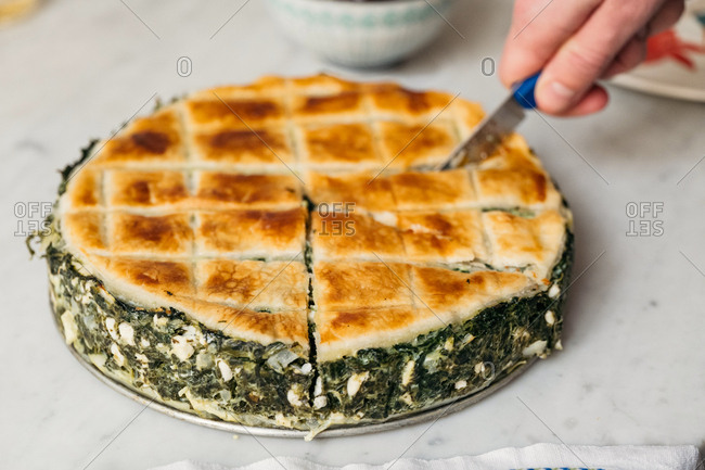 Person slicing a freshly baked spanakopita