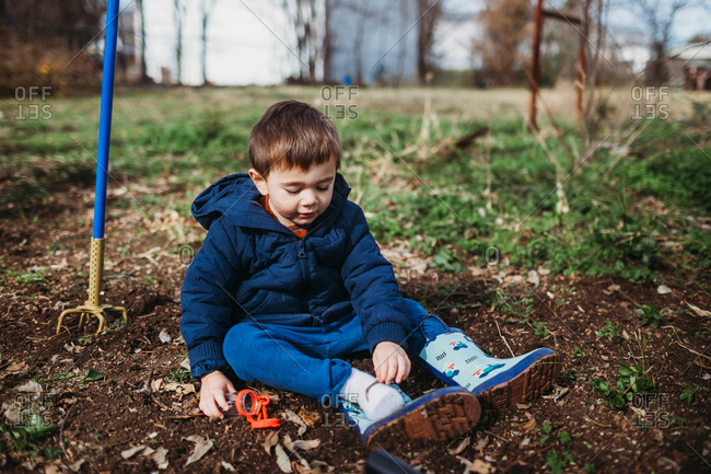Toddler boy looking for bugs in the dirt