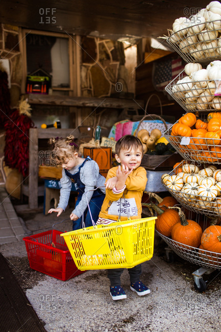 Two kids holding baskets at a farmers market