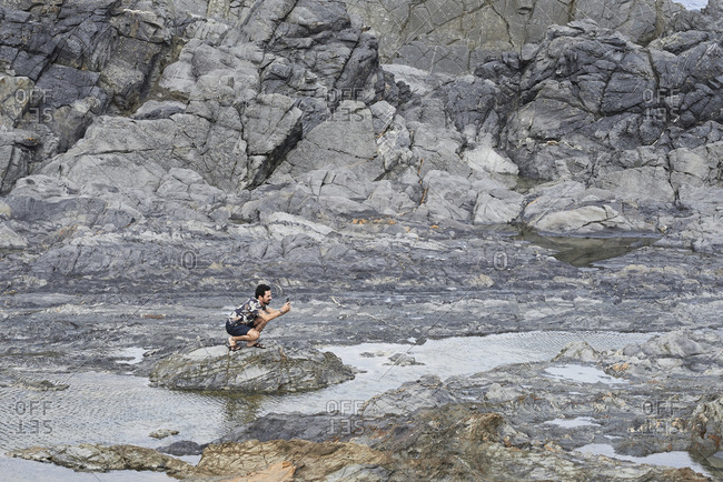 Brunette solo traveler exploring rugged terrain lunar landscape taking photos.