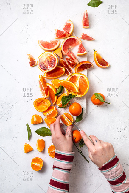 Citrus fruit being cut on cutting board with white marble background