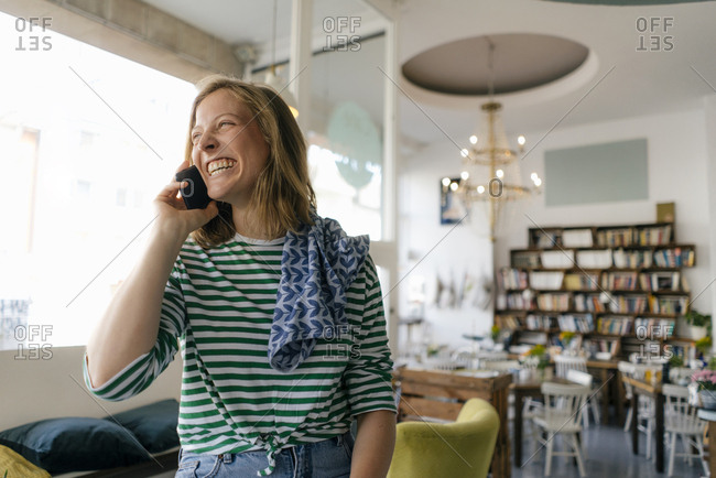 Laughing young woman on cell phone in a cafe