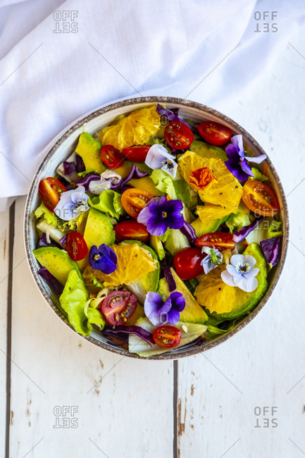 Bowl of mixed salad with avocado- tomatoes and edible flowers